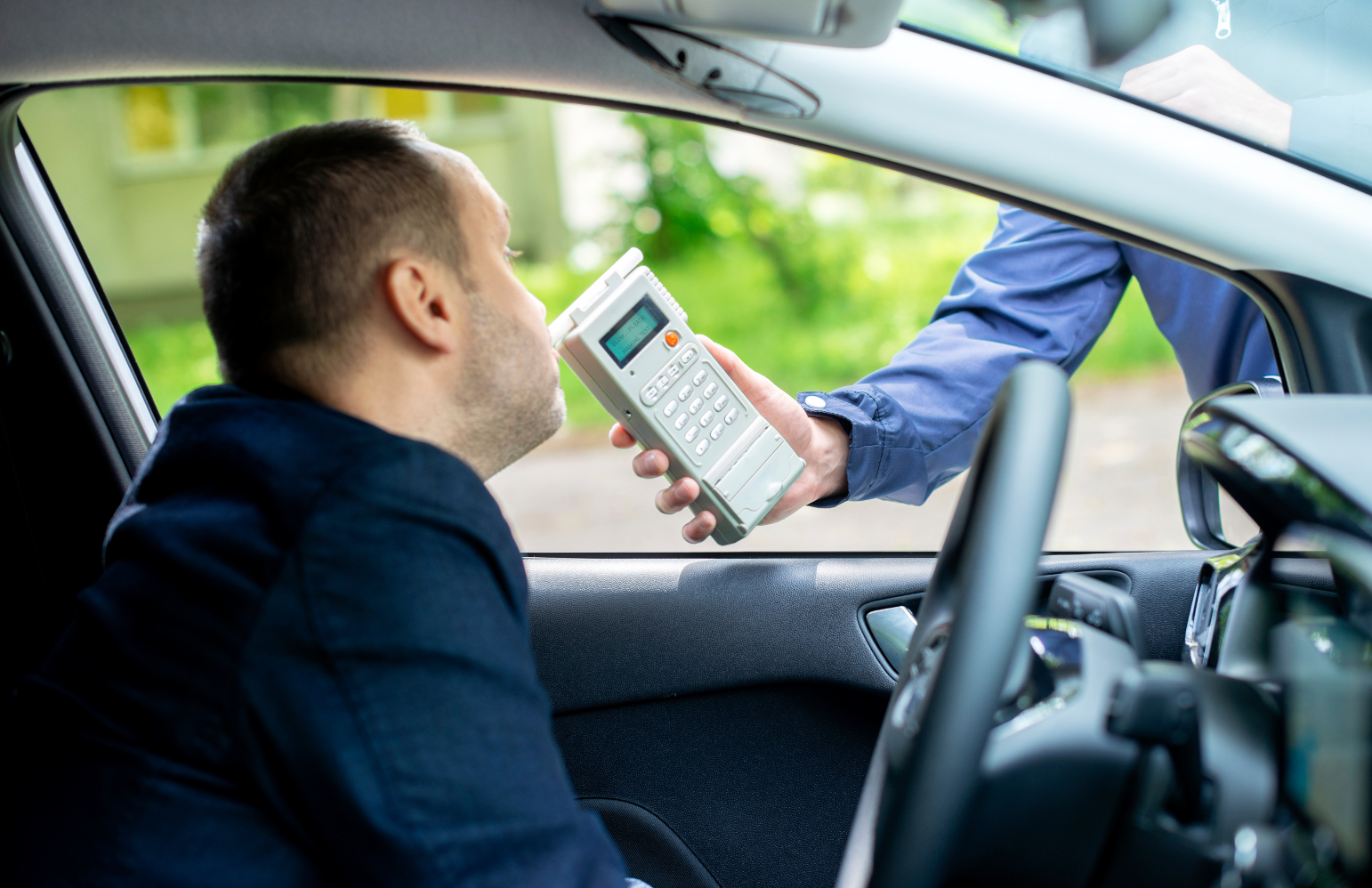 Driver blowing into a breathalyzer during a DUI traffic stop in Miami, Florida.